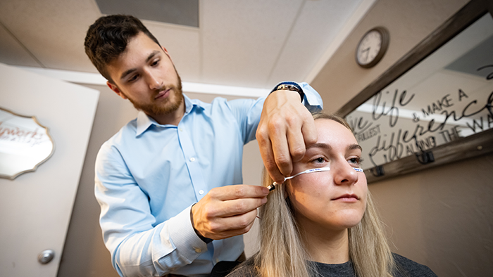 A young man performs a vision procedure on a young woman