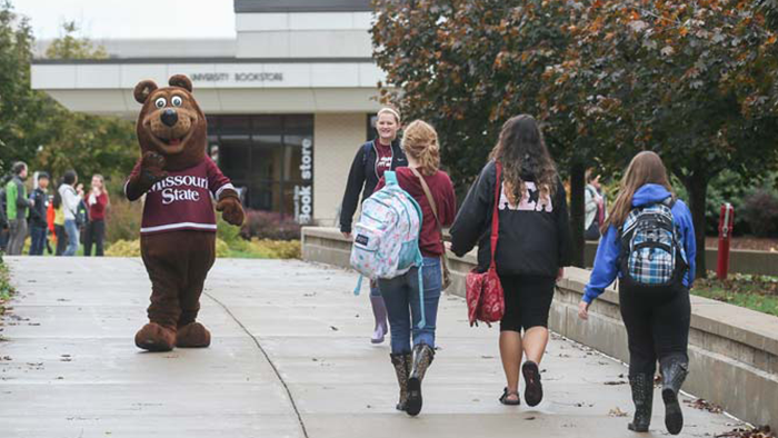 Boomer Bear greeting students on the sidewalk.