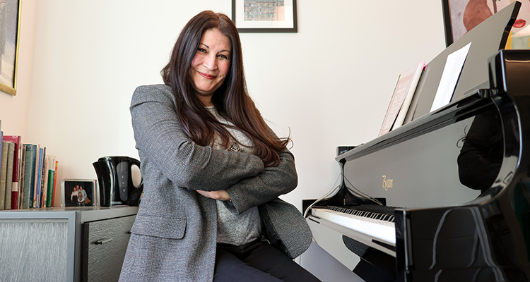 Dr. Ann Marie Daehn poses for a photo, seated at her piano.