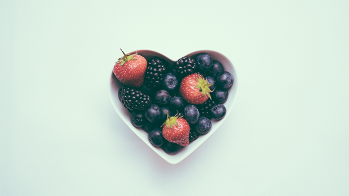A heart-shaped bowl filled with a mix of berries