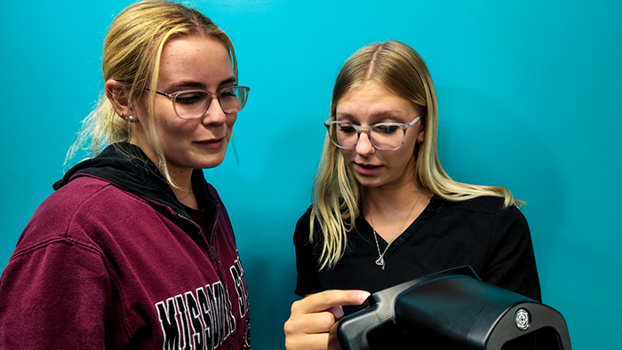 An AmeriCorps member shares the results of a vision screening with a Missouri State student