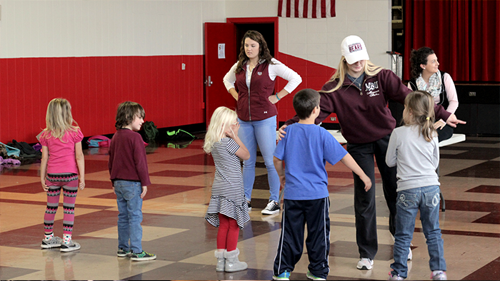 Two MSU students instruct a line of Robberson elementary children