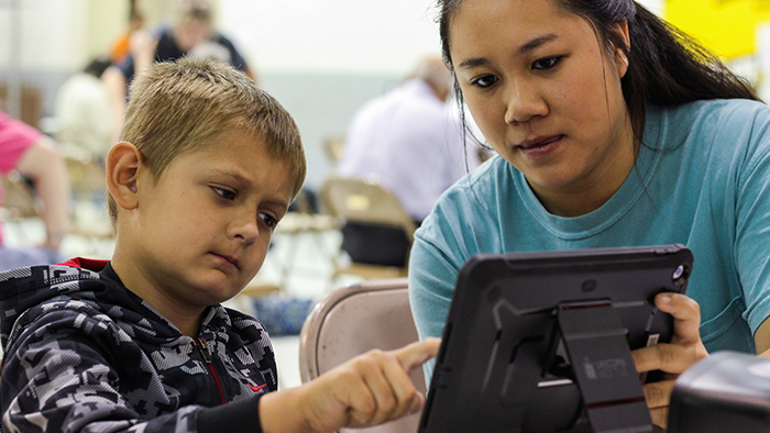 A service-learning student guides a child through a vision test