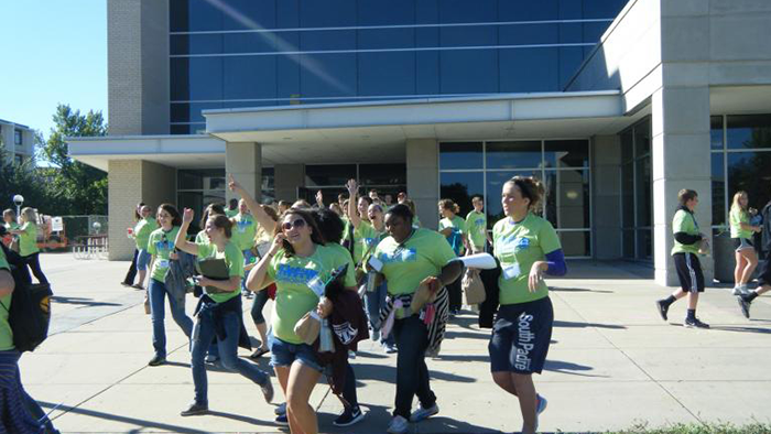 A group of student set out from Plaster Student Union wearing green Walkable Springfield project shirts