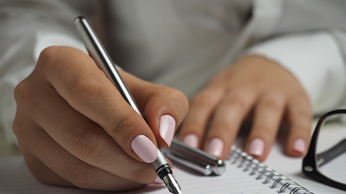 Close up of hands using an ink pen on a notebook