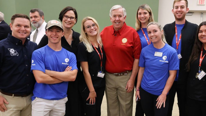A group of AmeriCorps people pose at an event with the governor