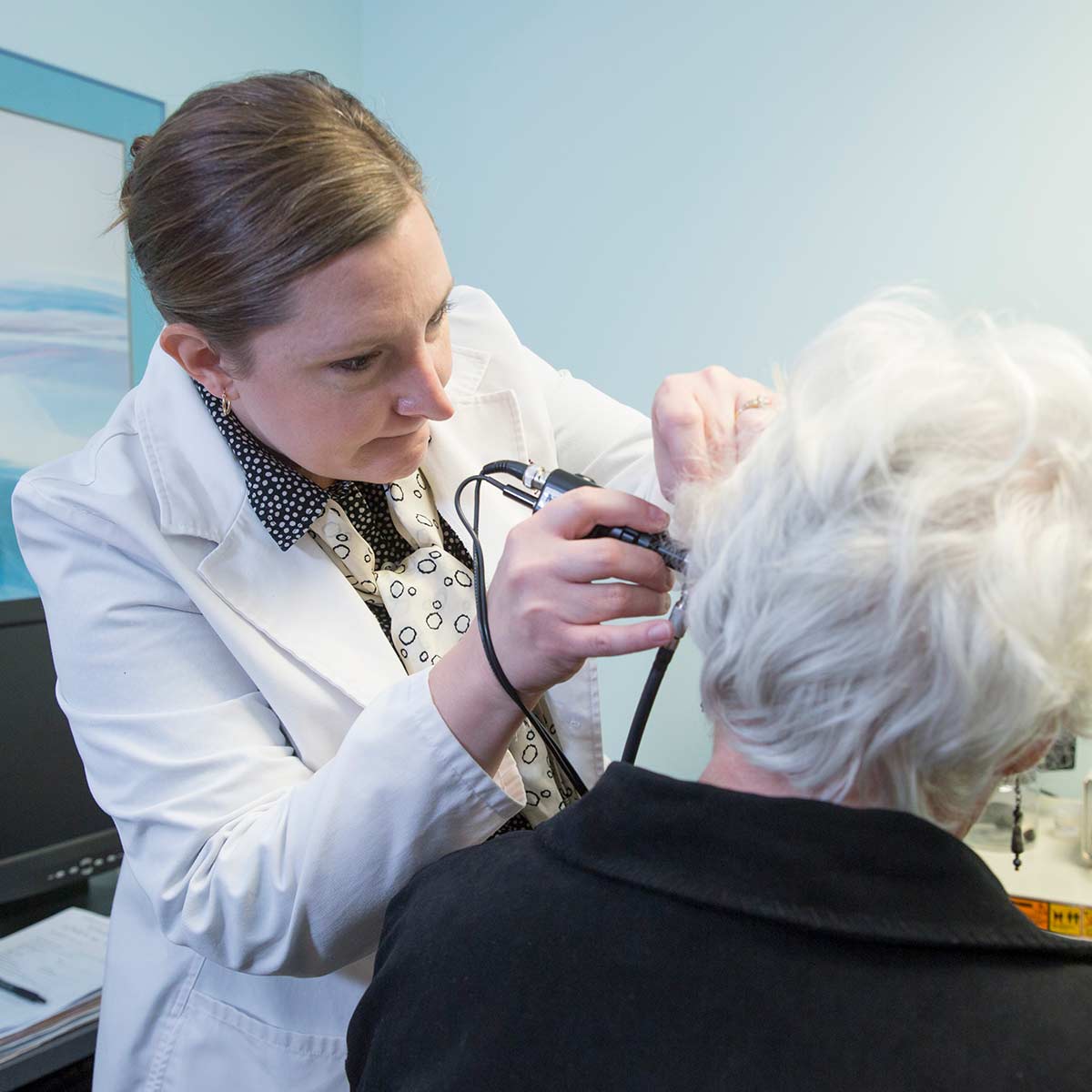 An audiology student conducts a hearing exam on an elderly patient at the clinic on campus