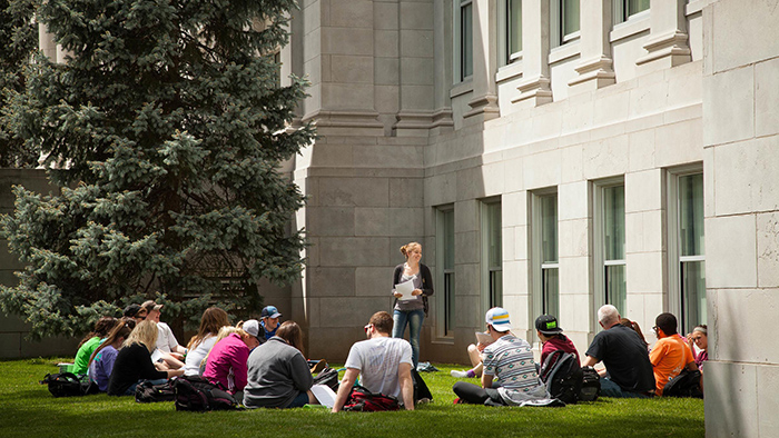 class of students sitting on grass outside of Siceluff Hall
