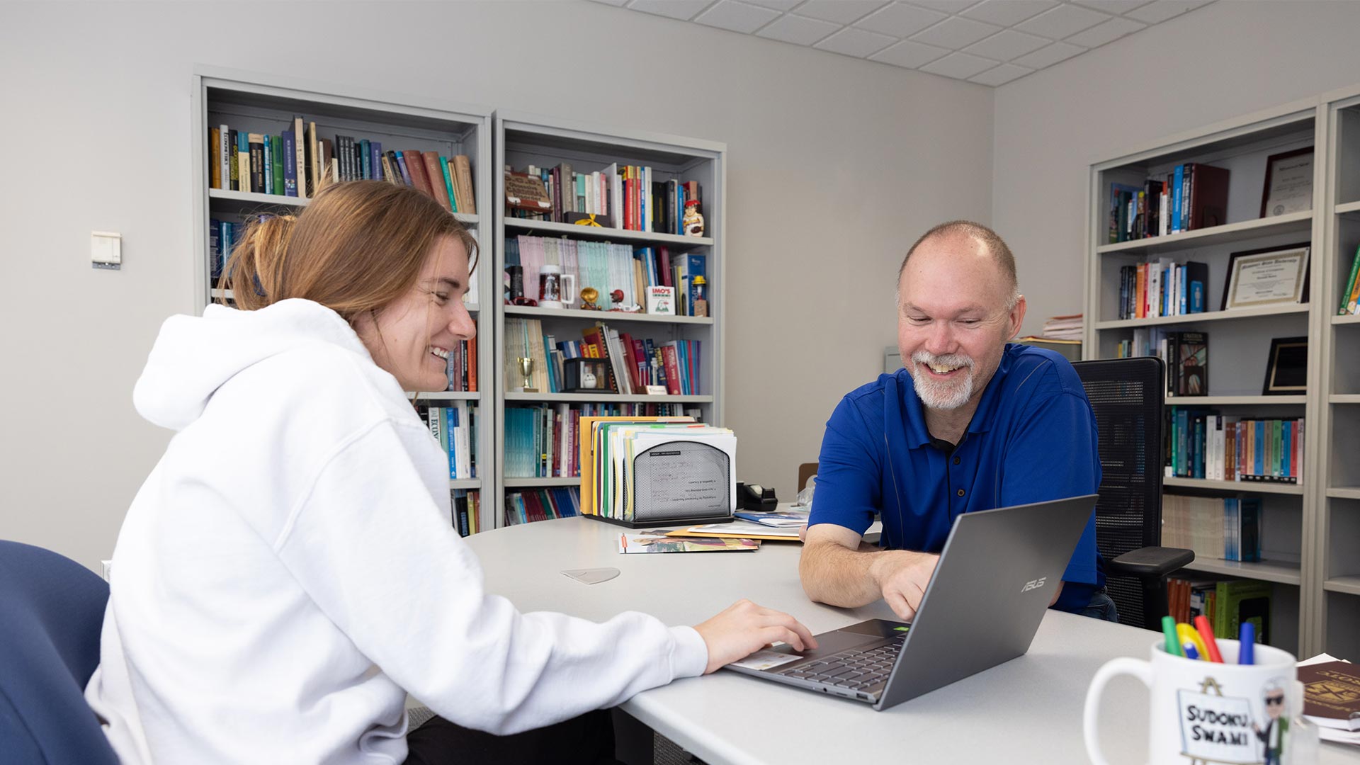 Professor and student looking at information on a laptop.