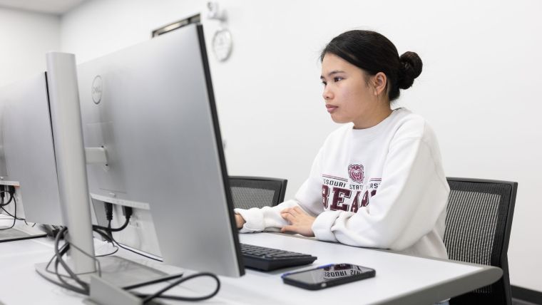 Professor and student looking at information on a laptop.