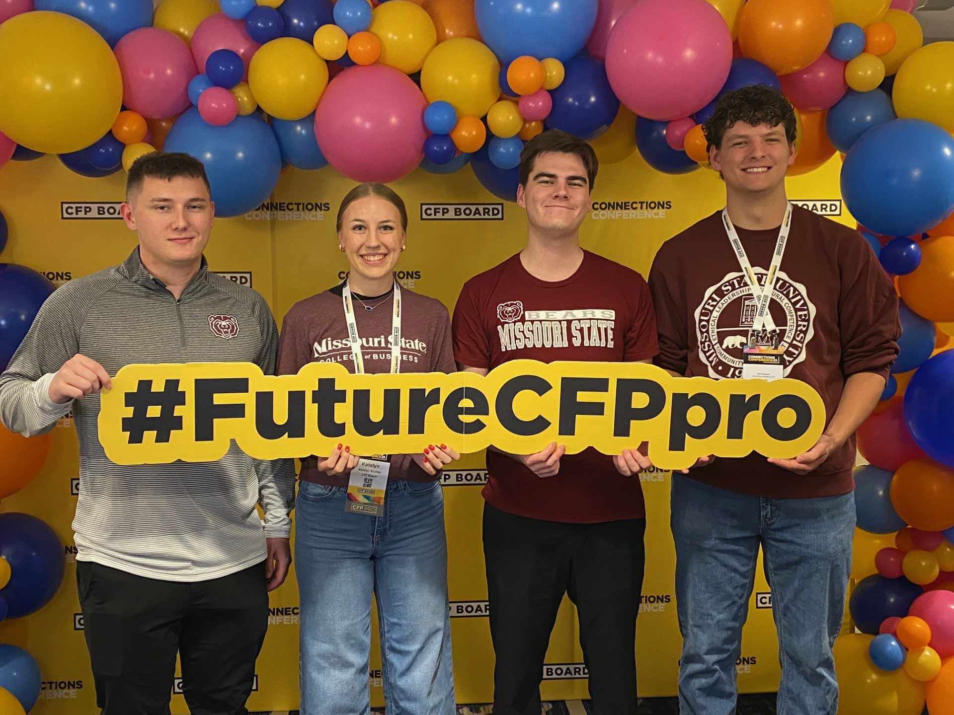 Four financial planning students, all wearing Bearwear, hold up a #FutureCFPpro sign