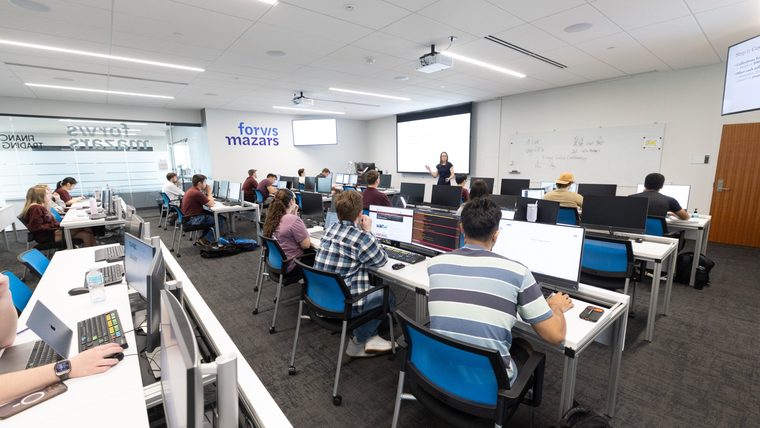 Students at computer workstations in the Forvis Mazars Financial Trading Lab during a lecture.