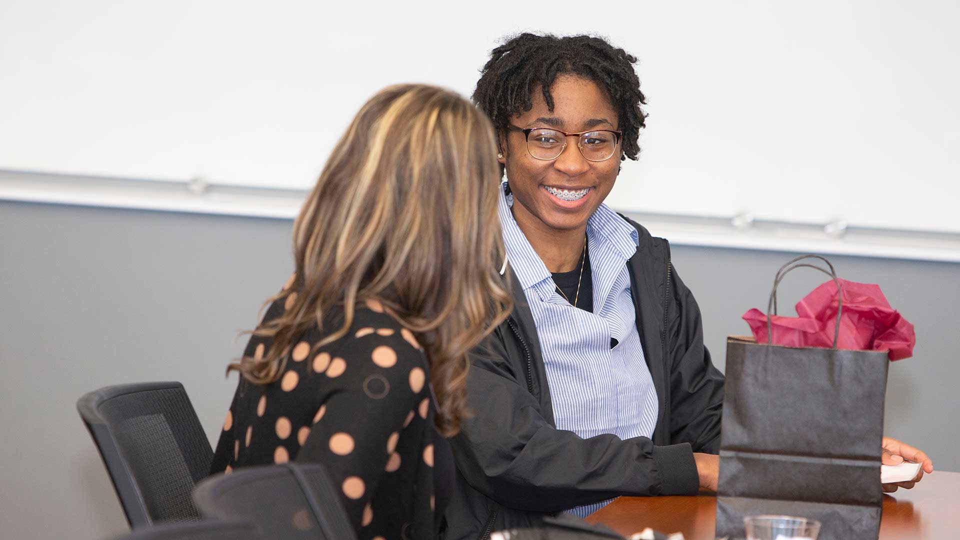 A business student smiling as she talks to a corporate mentor.