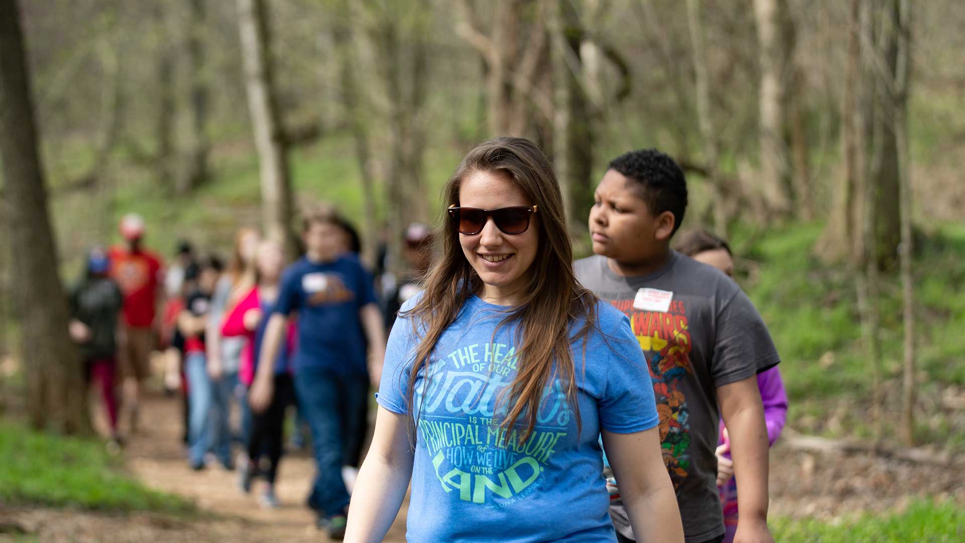 A group of students get active by taking a stroll through a wooded area.