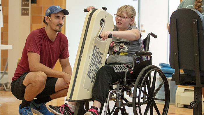 Kinesiology student working with child in adaptive physical education lab.