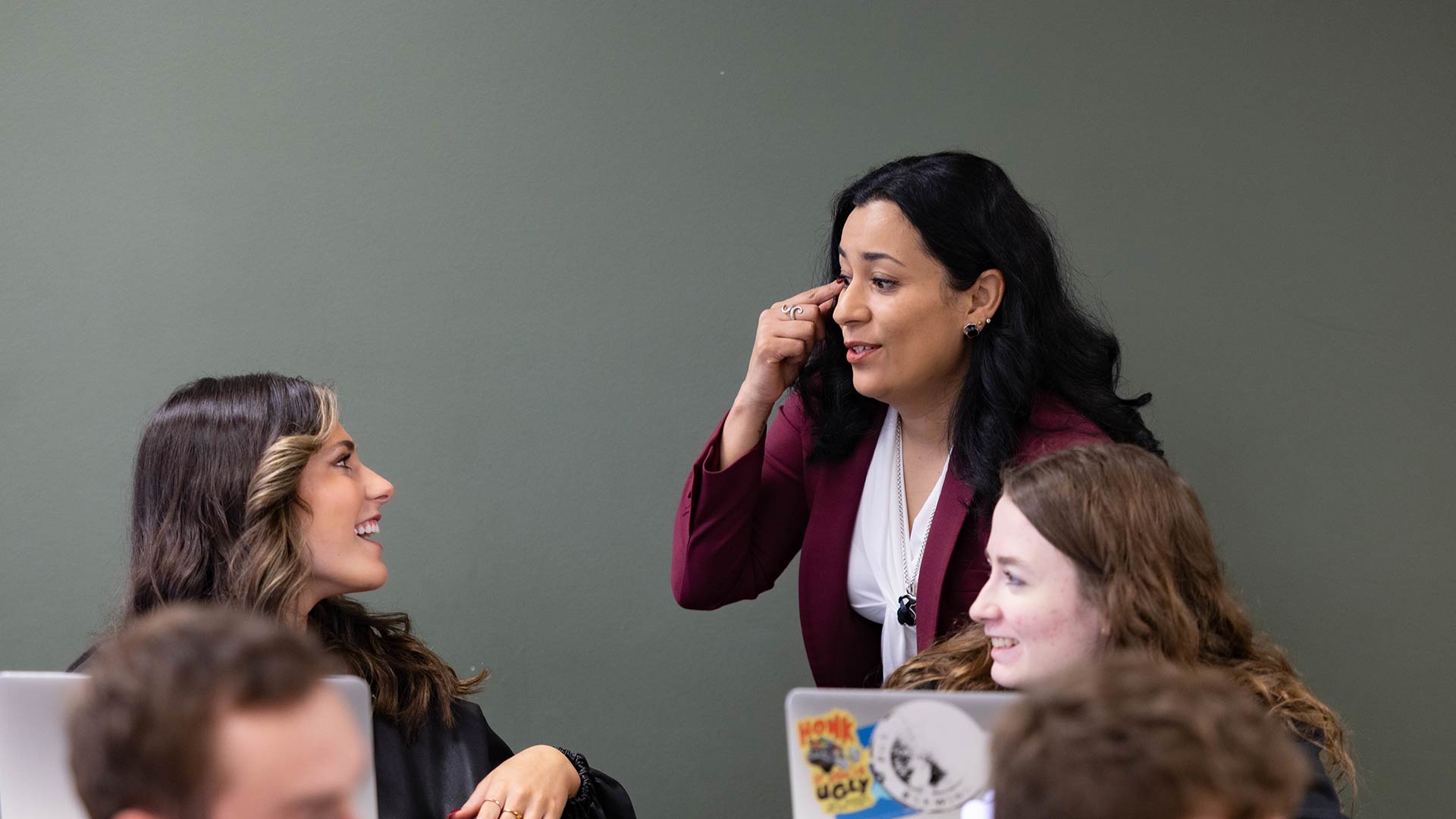 A language professor talks to two students during class.