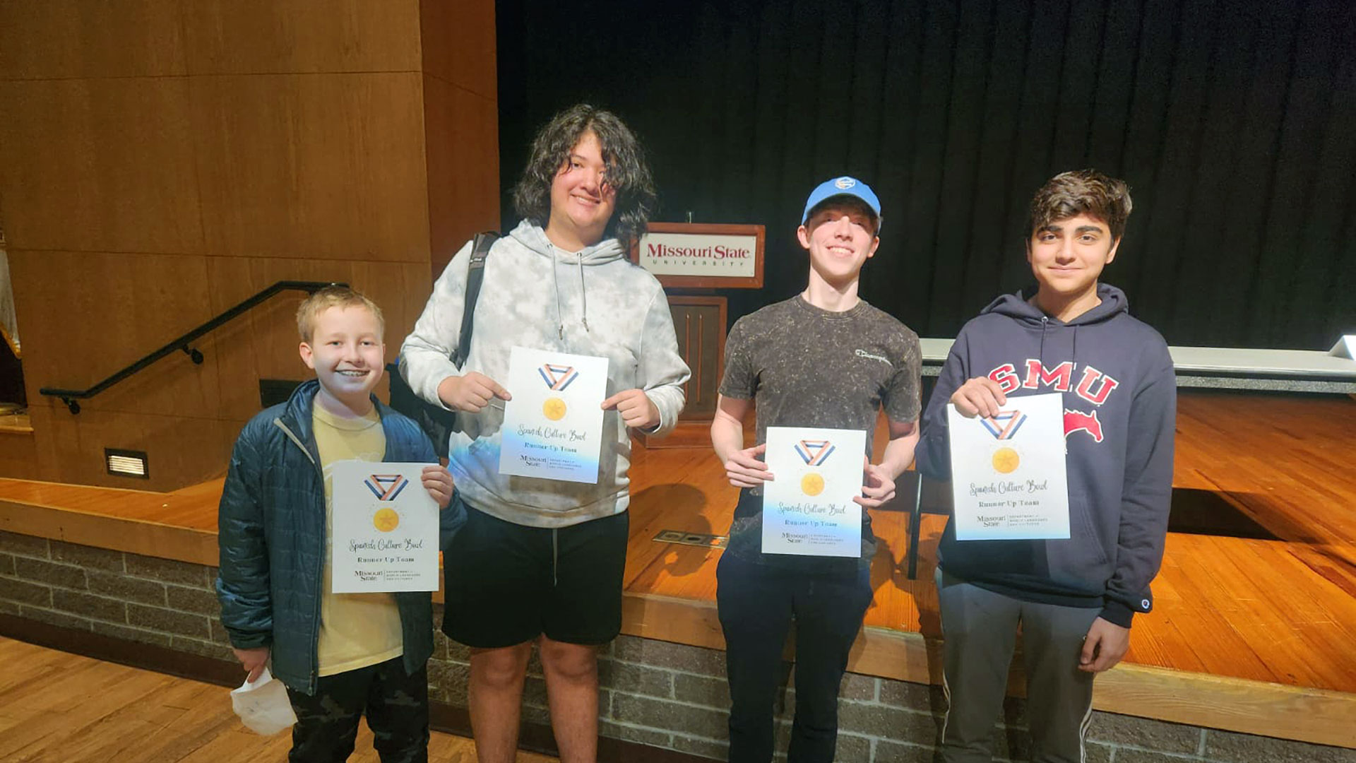 Four young students hold award certificates