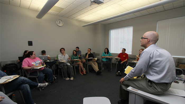 A religious studies professors has a class discussion with a group of students.