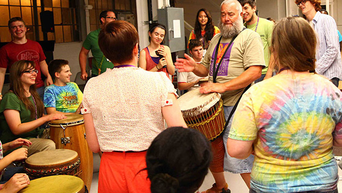 Students surround Ray Castrey drumming the bongo