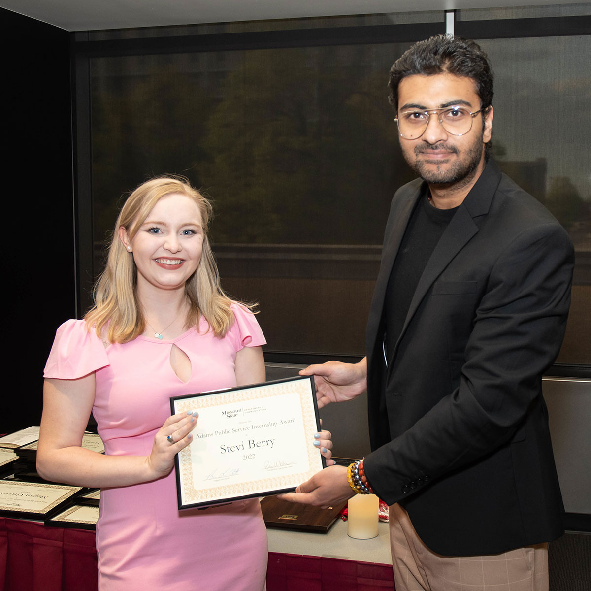A student receives a framed certificate from a member of faculty.