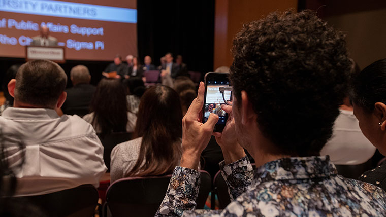 An audience member takes a picture with his phone during a U.S. Citizenship Naturalization Ceremony at the Plaster Student Union.