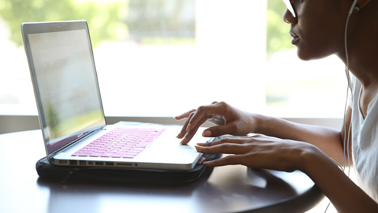 A woman uses the mousepad on her laptop to work on a project.