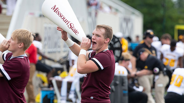 Two cheerleaders shout into megaphones.