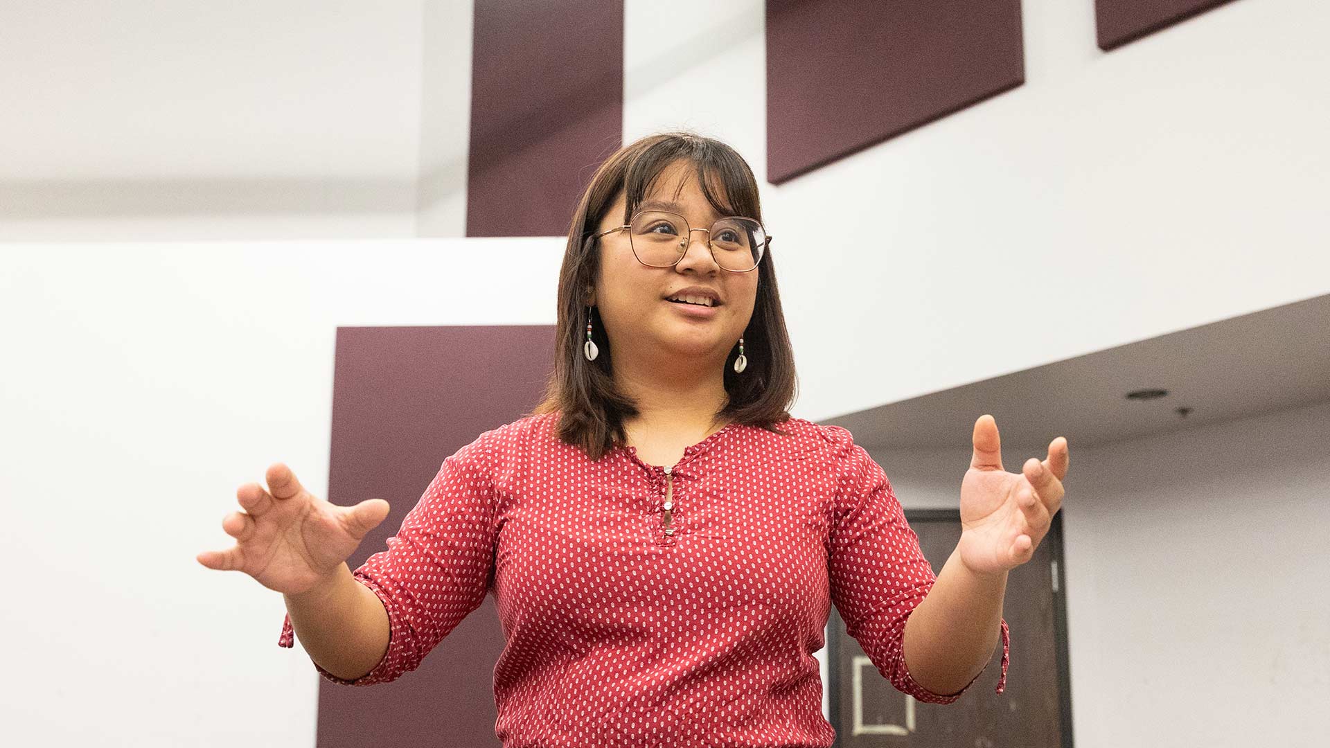 A graduate student conducts a choir group during rehearsal.