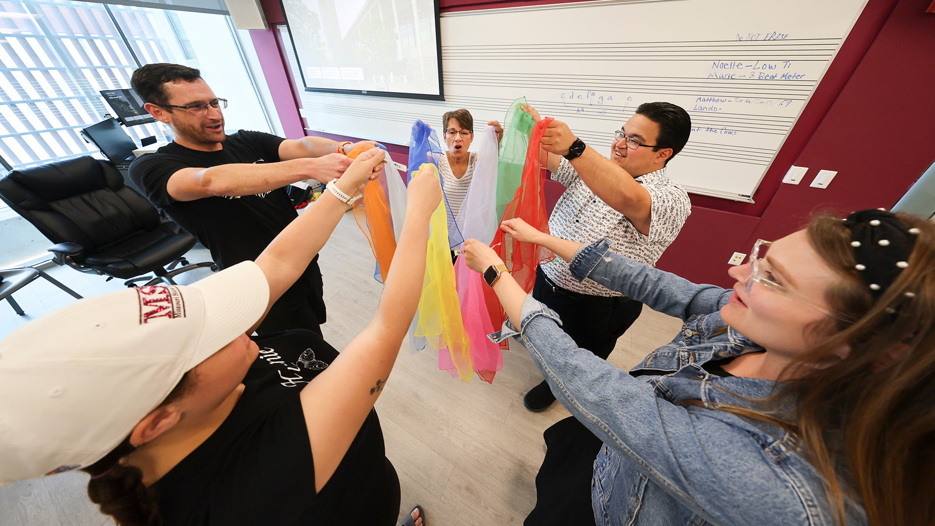 Students in circle hold colorful scarves