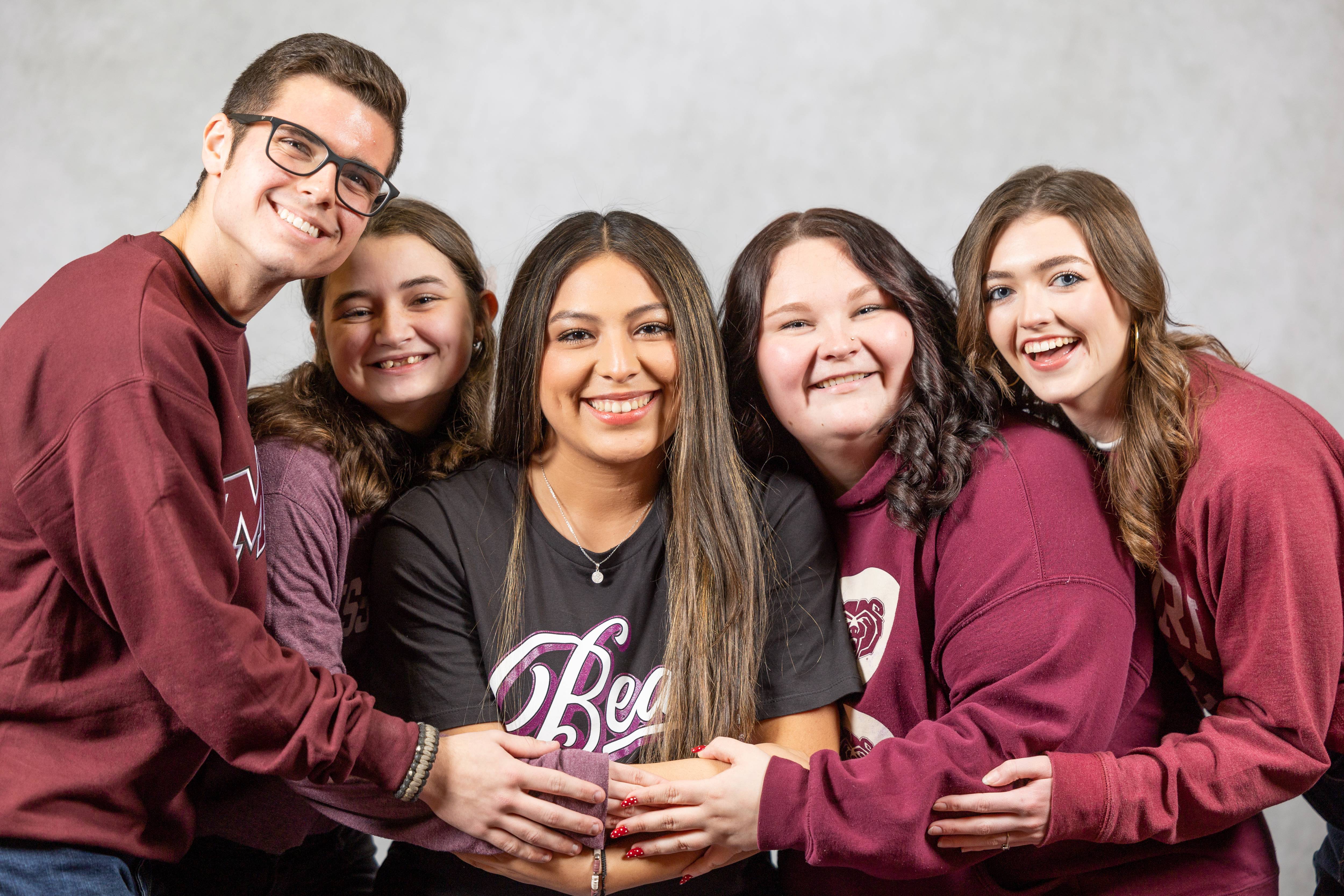 Students hugging and smiling at the camera