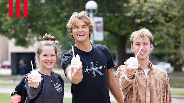 Three students holding out their containers of pineapple whip. 