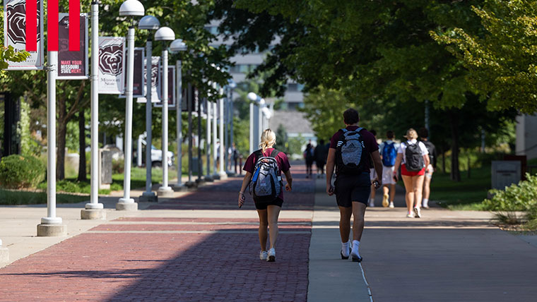 Students walking past Missouri State University banners on campus.
