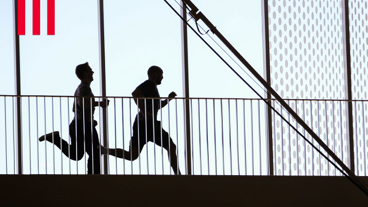 Two individuals running track at a recreation facility.