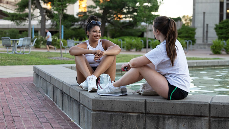 Two Missouri State students sitting at the Hammons Fountains visiting.