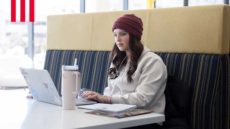 Missouri State student sitting on a bench at a table with laptop.