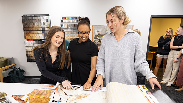 Individuals standing at a table reviewing interior design swatches.