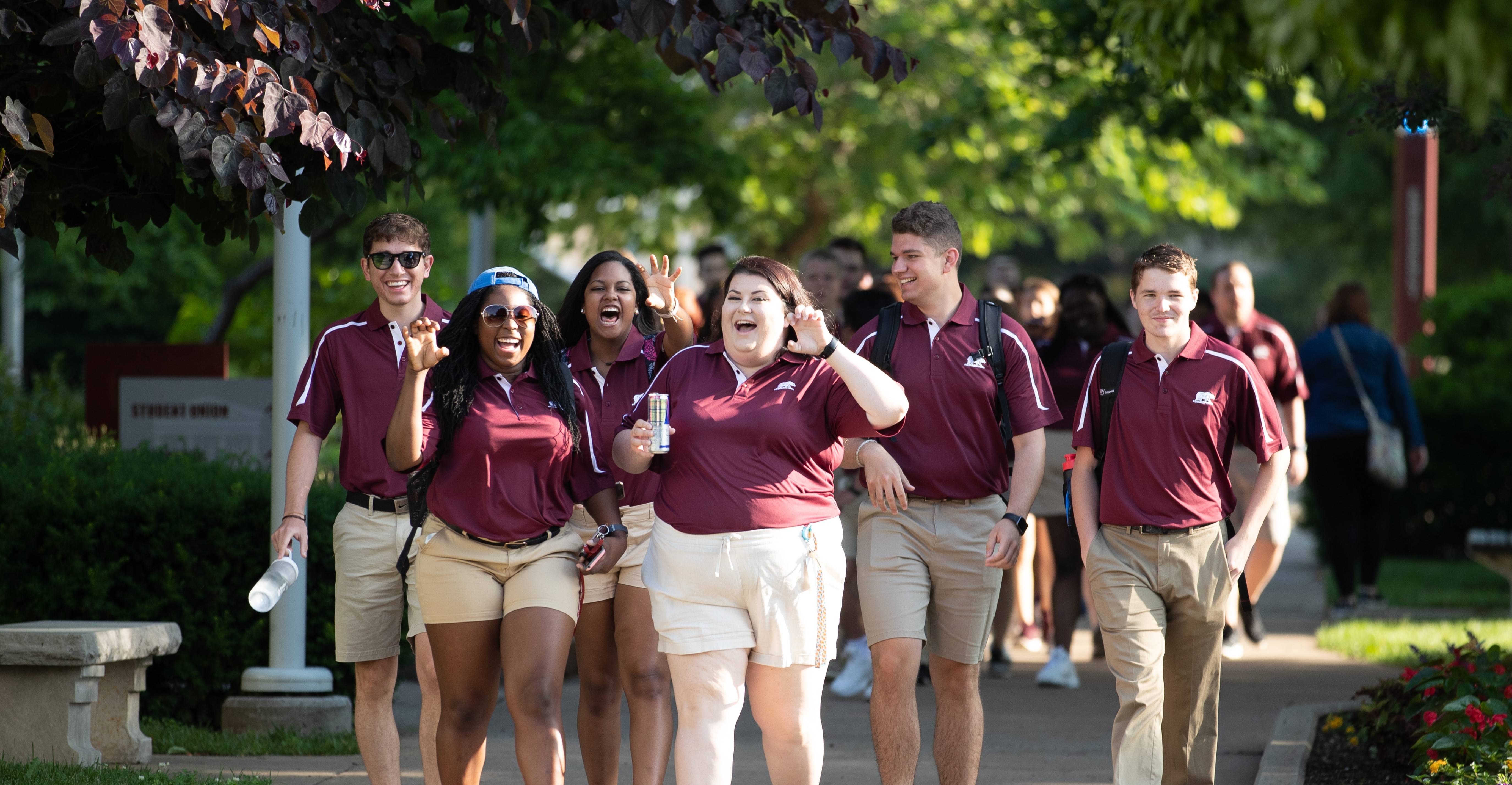 A group of students walking through campus laughing together. 