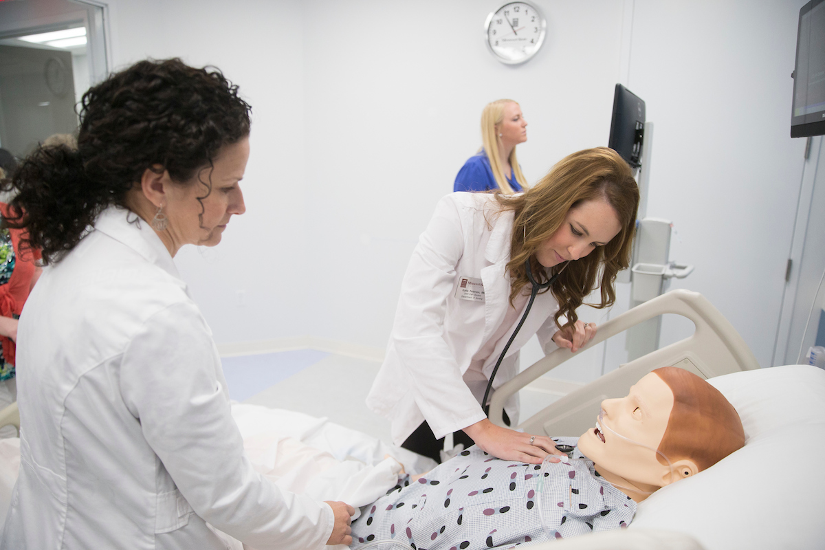 A Missouri State nursing student using a stethoscope in the MCQueary Family Health Sciences Hall