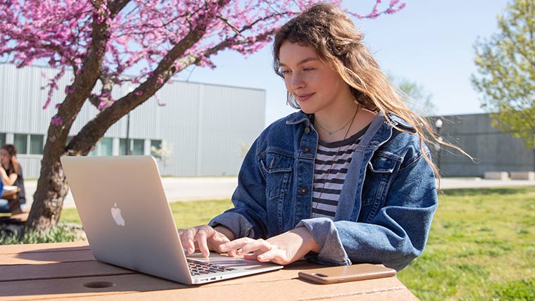 Student studying on her laptop outside on a nice, sunny day..
