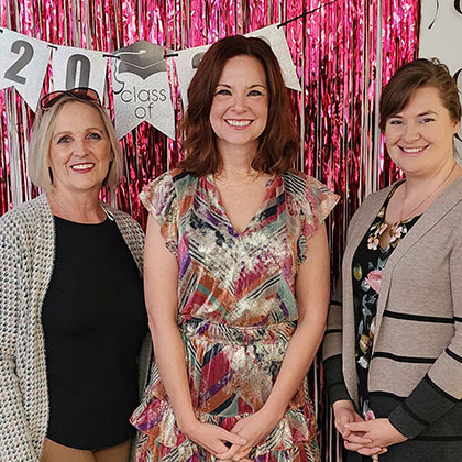 A smiling graduate with nursing faculty.