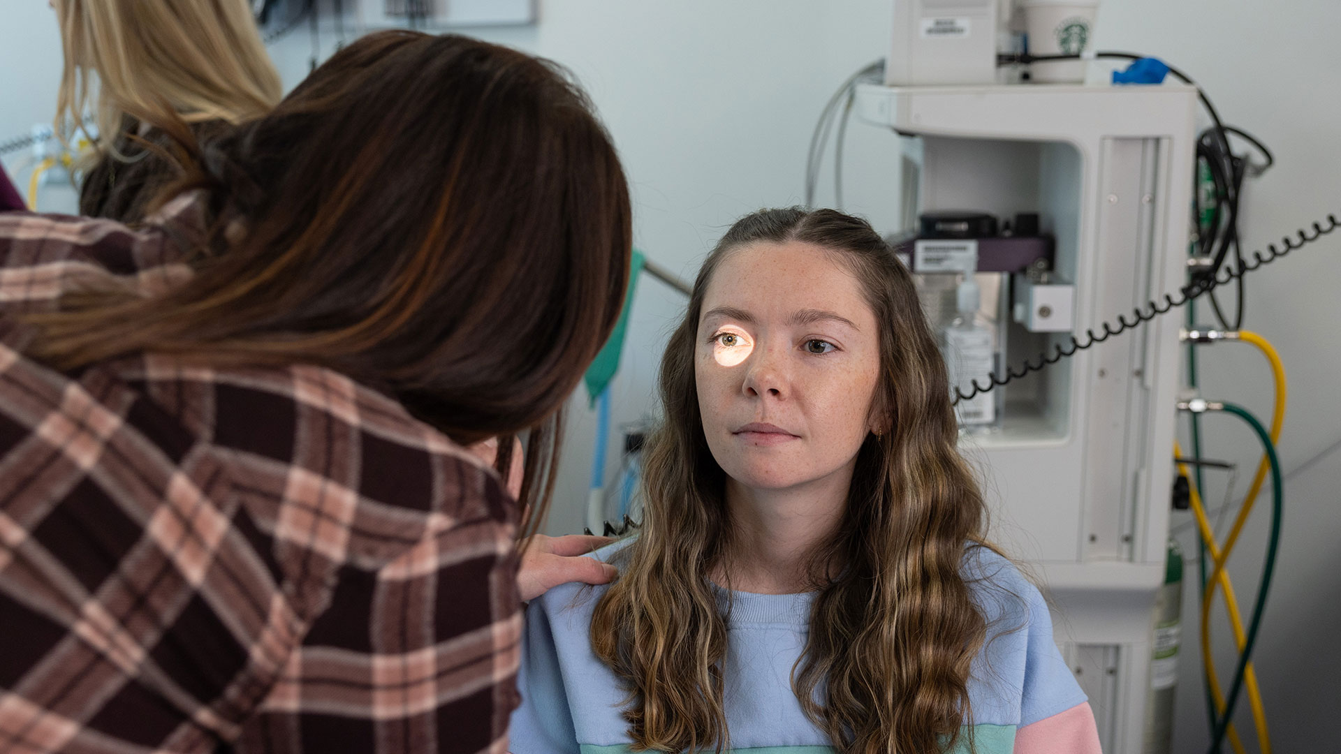 A nursing student shines a light into her classmate's right eye during a practice eye exam.