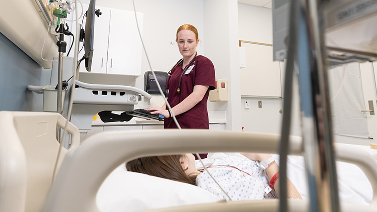 A nursing student talking with a mock patient in the sim lab.