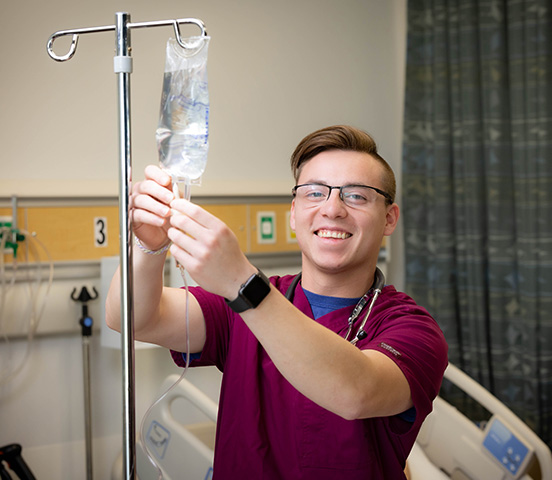 Missouri State student in maroon scrubs in the simulation lab.