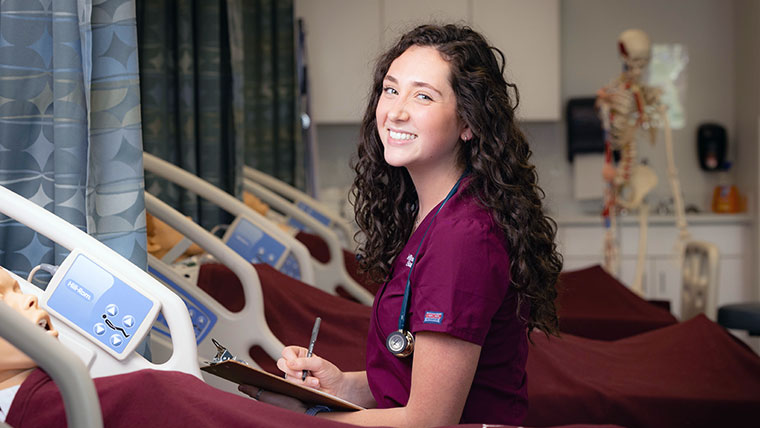 Smiling Missouri State nursing student with clipboard in hand.