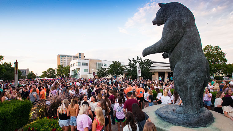 Missouri State students are gathered on the lawn near the bronze bear statue.