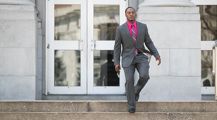Student in business suit walking down stairsteps.