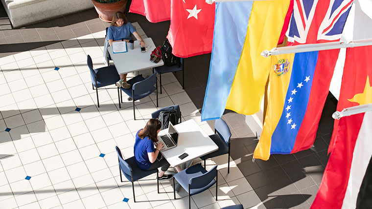 Missouri State students at their laptops in Strong Hall where flags of the world are being displayed.