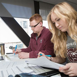 Two students in Missouri State BearWear looking over papers.