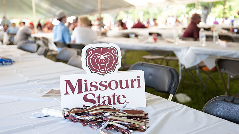 A plastic Missouri State nameplate and maroon tassel placed on a table at Bearfest Village.