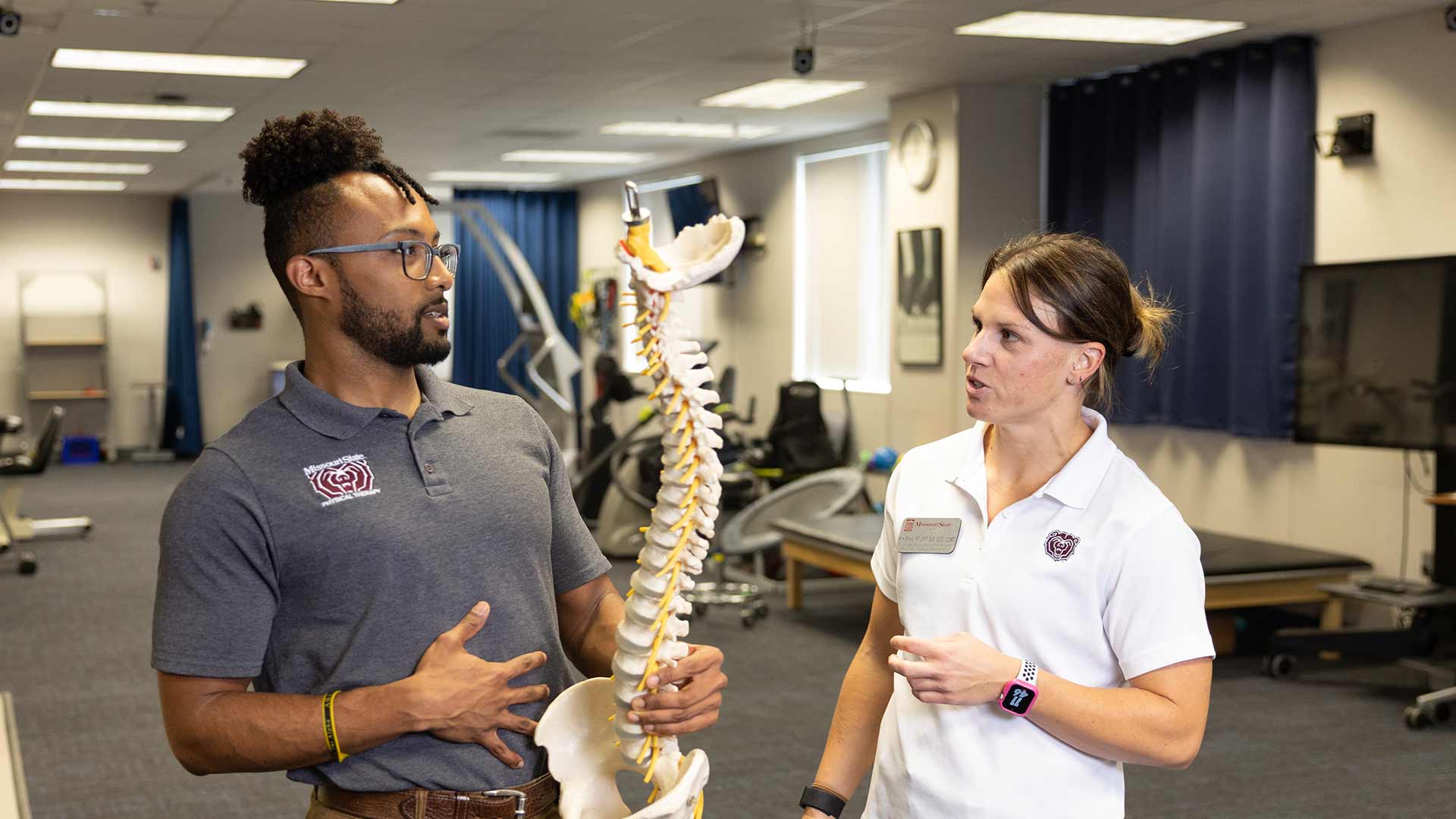 A physical therapy student and professor Dr. Kim Ennis look over a model of the human spine.